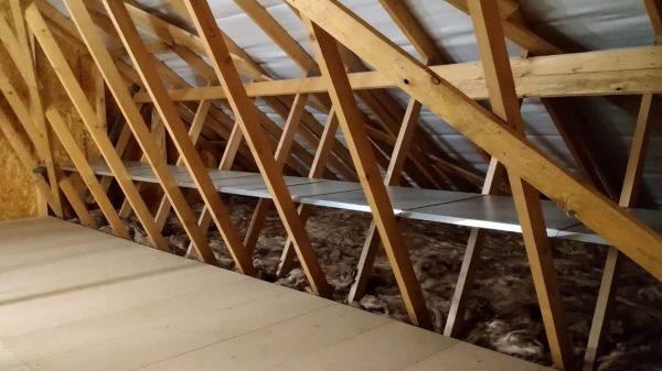 An attic with a metal shelf fitted within the ceiling joists.