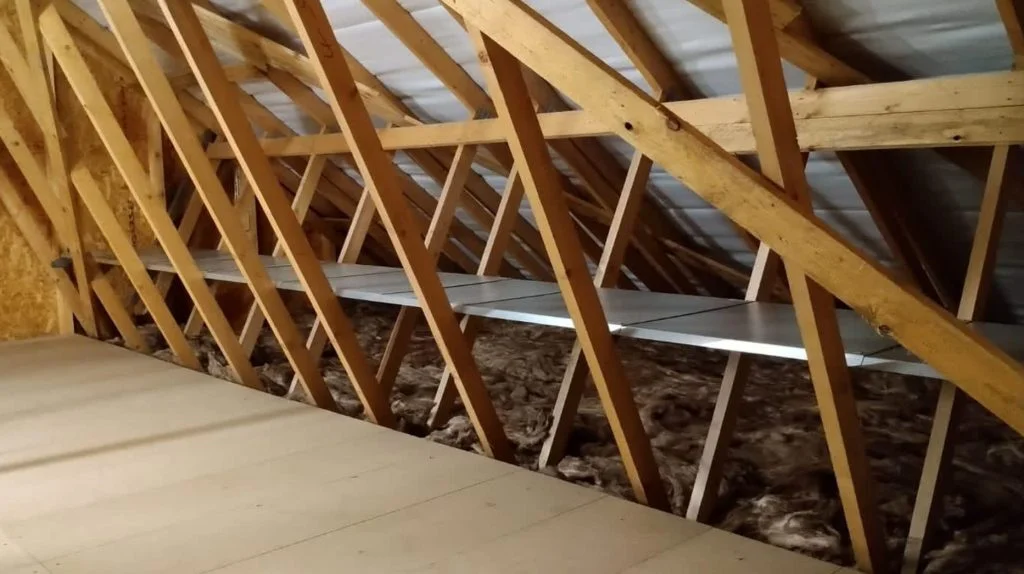 An attic with a metal shelf fitted within the ceiling joists and a boarded walk way.