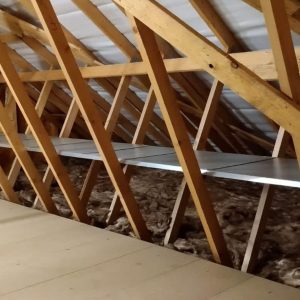 An attic with a metal shelf fitted within the ceiling joists and a boarded walk way.
