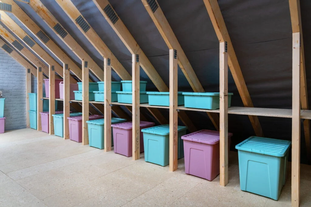 A large attic space with multiple attic shelves installed to hold plastic storage boxes.